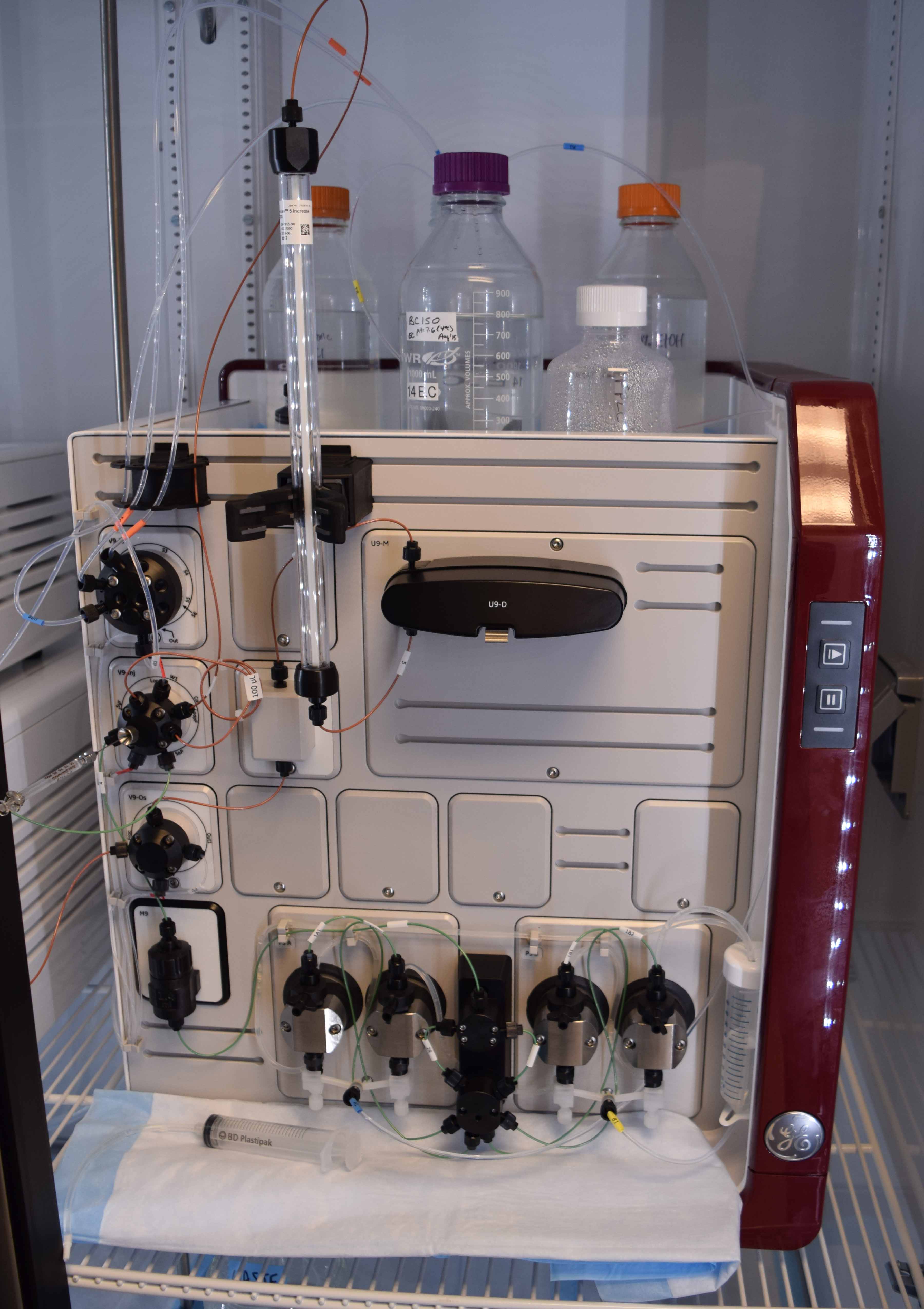Picture of the lab's Fast Protein Liquid Chromatography (FPLC) machine, sitting in a large refrigerating unit.