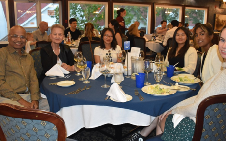 Six members of the Pearson Lab team sitting together around a large circular dinner table during a social outing.