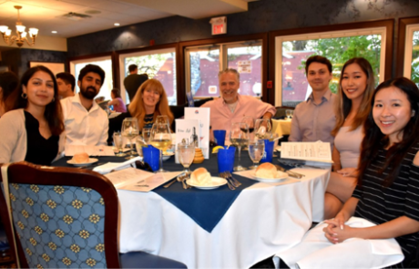 Seven Pearson Lab team members, including Dr. Pearson, smiling together at a formal dinner table.