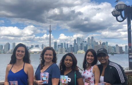 Group of 5 woman posing in front of the Toronto skyline each holding a bag of gummy candy.