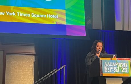 Presenter standing at a podium speaking into the microphone at a conference.