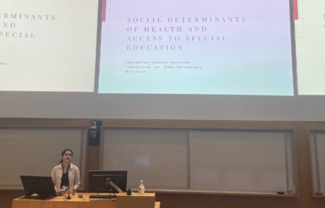 A woman in front of a podium standing by a powerpoint presentation titled "Social determinants of health and access to special education".