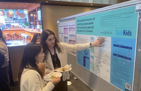 One woman presenting her poster to a viewer, the poster is titled "Social determinants of health are associated with access to special education in Canada".