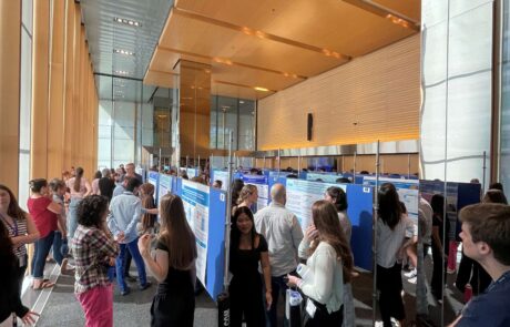 A room full of people and research poster boards at a research conference.