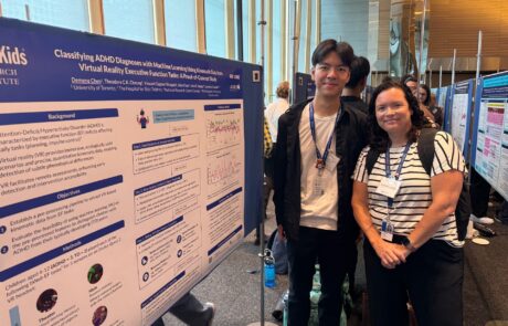 Student and his supervisor standing together beside a research poster at a conference.