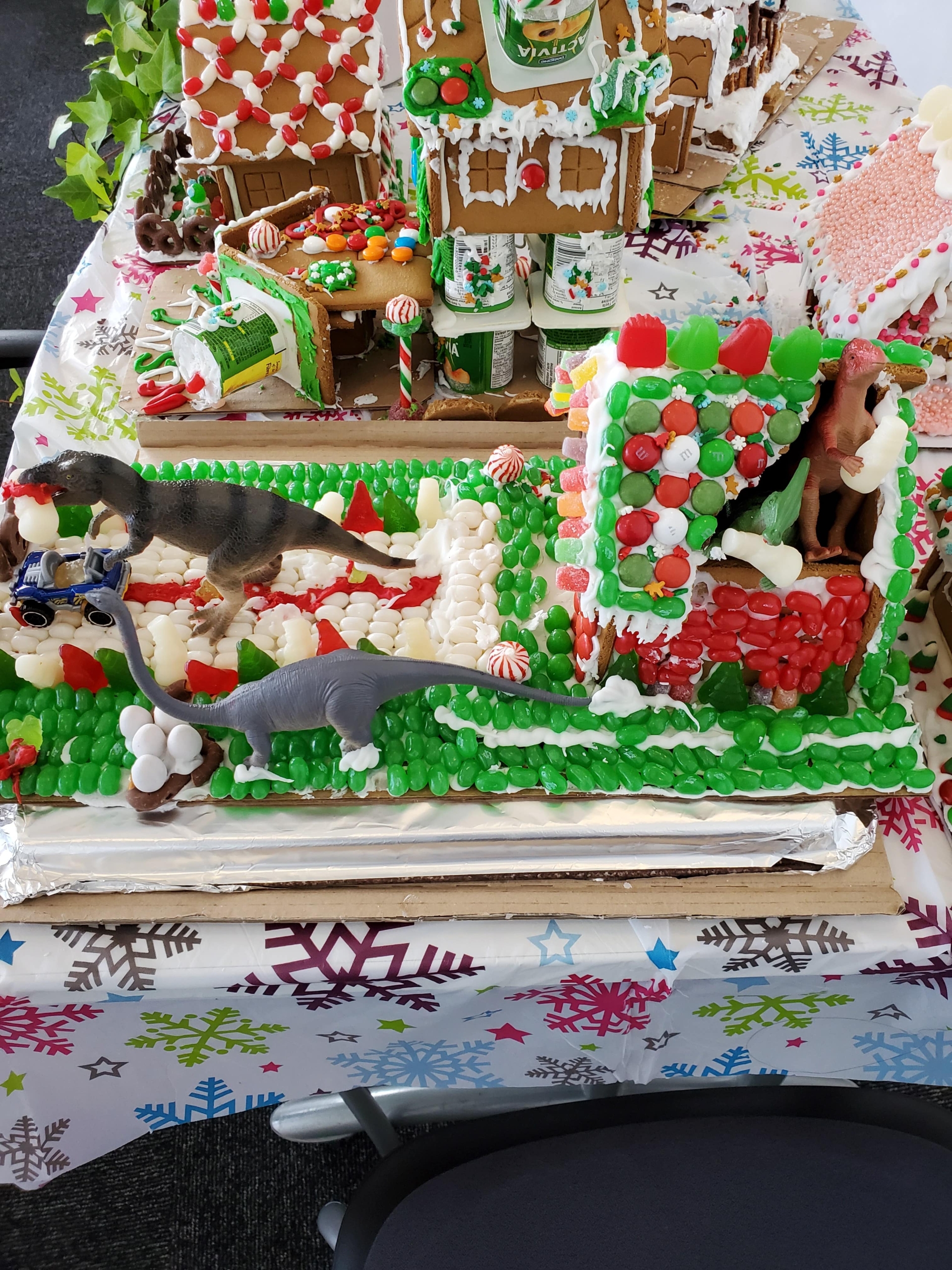 Ditlev Lab gingerbread house. There are dinosaurs on lawn in front of the gingerbread house.