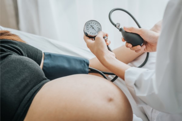 A doctor measuring a pregnant person's blood pressure