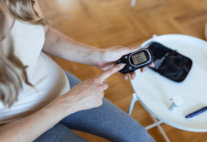 A pregnant woman is testing her blood glucose level using a fingerstick monitor