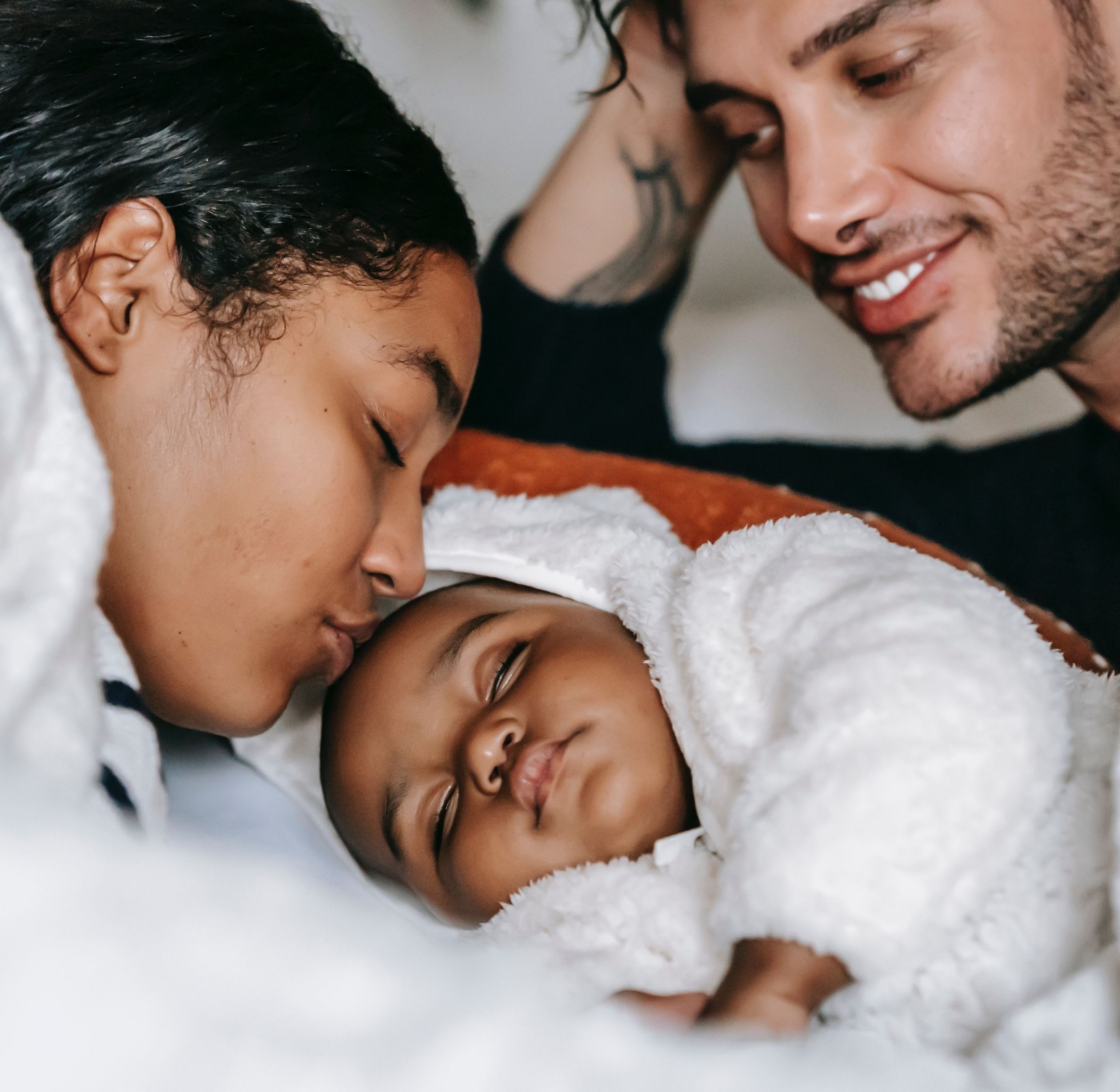 young parents of colour with their sleeping baby