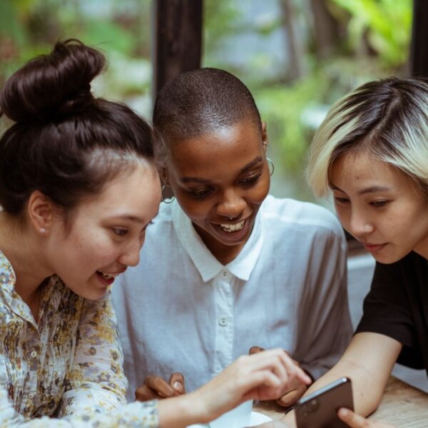 Click the image to go to the SHARE Project study page. The photo depicts young multiracial women looking at a phone