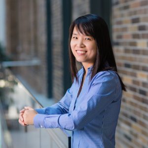 Dr. Yun Li leaning against a railing, smiling