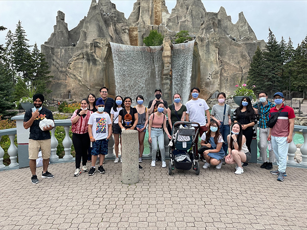 A group of adults and children standing in front of a large waterfall at Canada's Wonderland