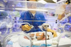 Photo of baby in an incubator with a nurse