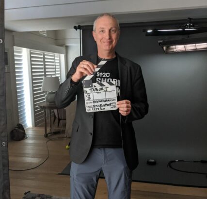 Dr. Uri Tabori holding a clapperboard for an interview with SU2C