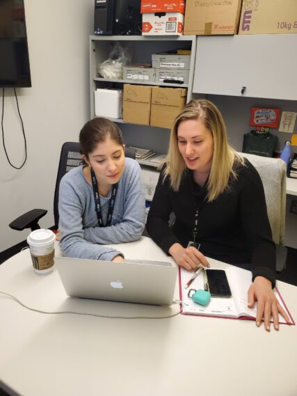 Ayse Bahar Ercan and Dr. Vanessa Bianchi sitting in front of a computer and coordinating a shipment from one of the Tabori Laboratory colaborators