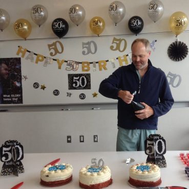 Dr. Michael Taylor stands in front of 50th birthday decorations