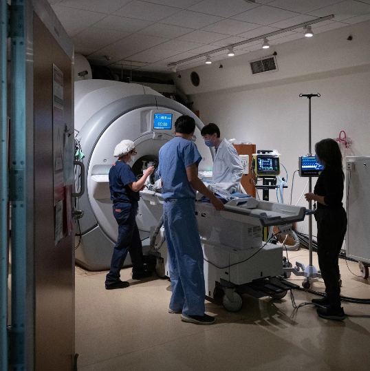 A photograph of a healthcare team prepping a patient for an MRI.