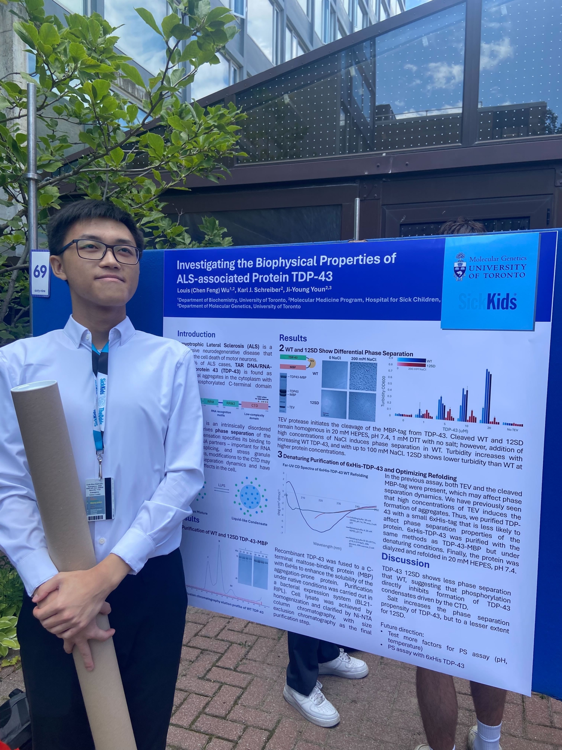Person standing beside a scientific poster titled “Investigating the Biophysical Properties of ALS-associated Protein TDP-43,” which includes sections like Introduction, Results, and Discussion with graphs and images. The person holds a poster tube and wears a lanyard with an ID badge.